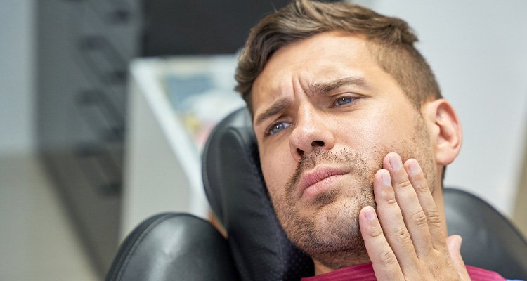 Patient in treatment chair struggling with toothache