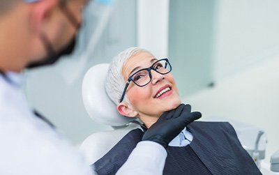Woman with black glasses smiling at dentist