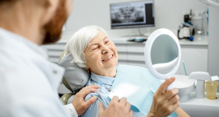 Senior dental patient admiring her smile in mirror