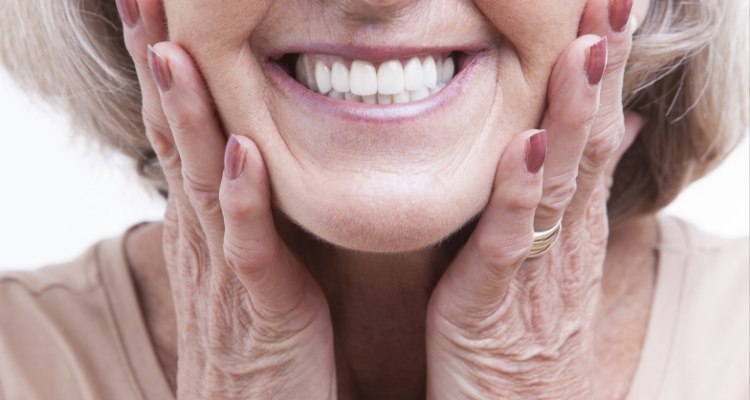 Close up of smiling senior woman touching her face