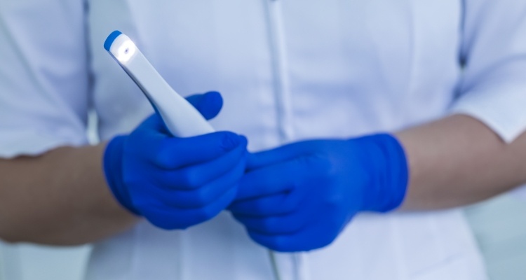 Two gloved hands holding a thin white intraoral camera