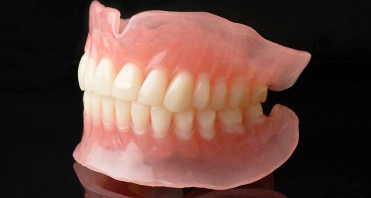 Full dentures sitting on dark reflective surface