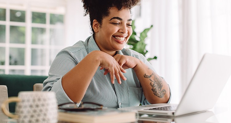 Woman smiling while working on laptop at home