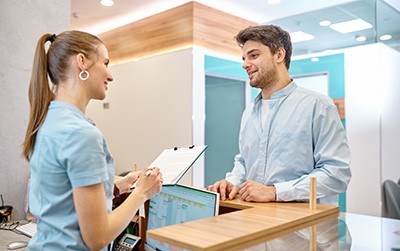 Patient and dental receptionist smiling in lobby