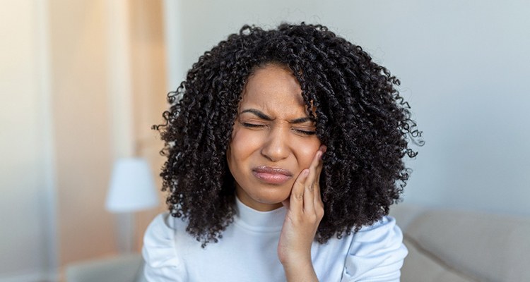 Woman holding her cheek in pain needing tooth extraction in Grapevine