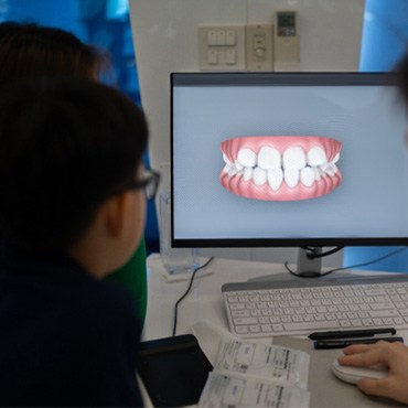 Dentist and patient looking at scan of their teeth on computer screen