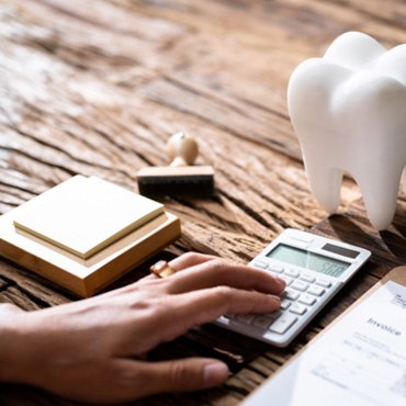 Patient calculating cost on desk next to computer and prop tooth