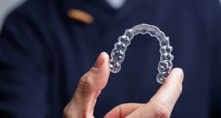 Hand holding an Invisalign aligner