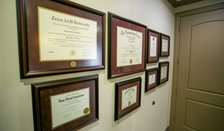 Several framed diplomas on wall of dental office