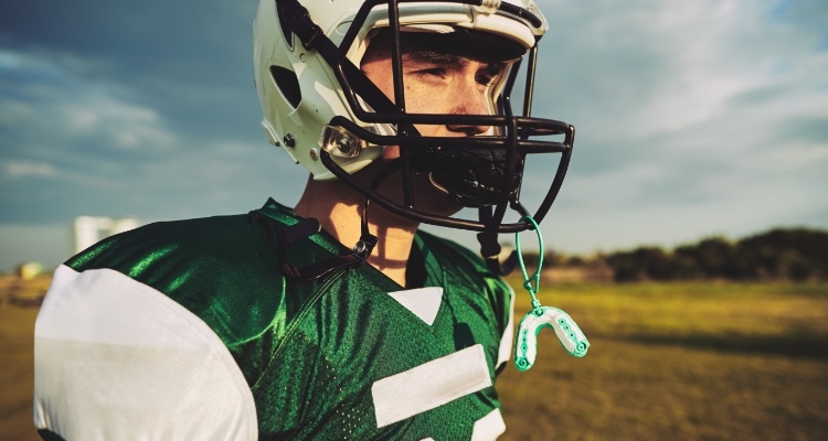 Football player with mouthguard hanging from his helmet