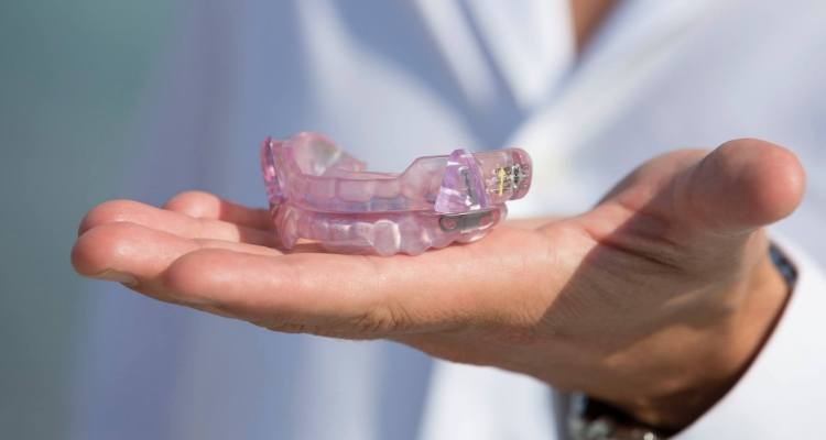 Hand holding a set of light purple mouthguards