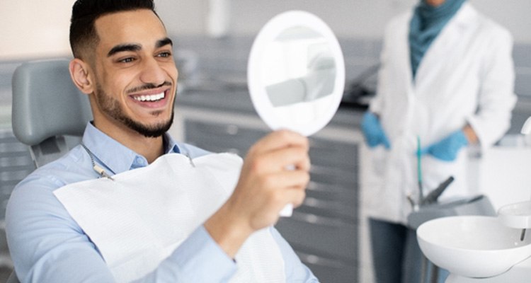 Man smiling at reflection in handheld mirror